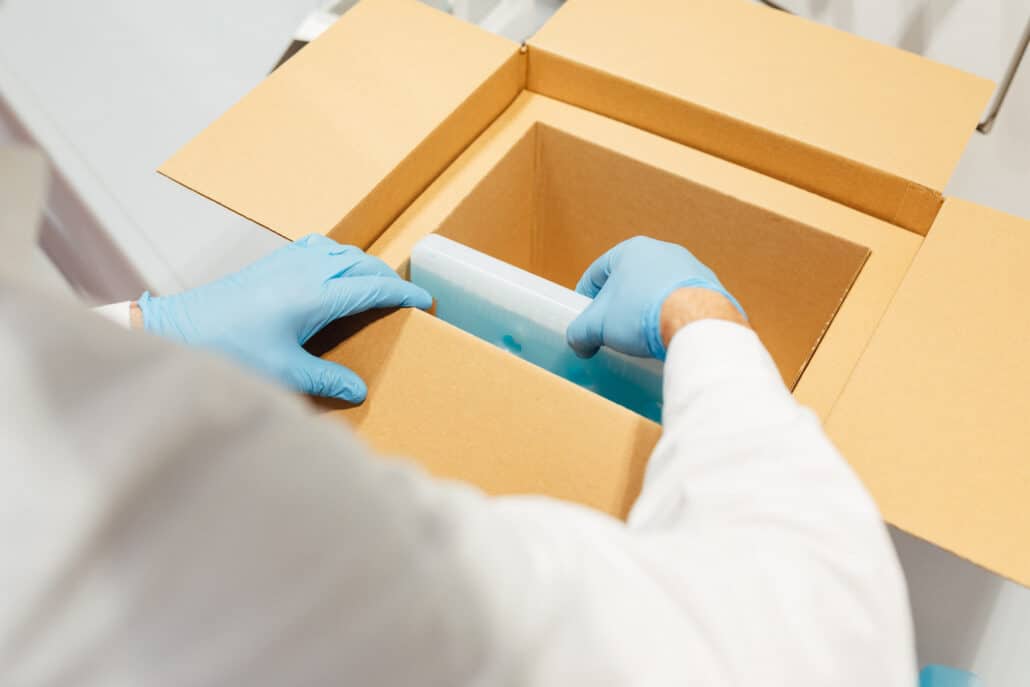 Gloved hands placing components inside a paper-based insulated shipper
