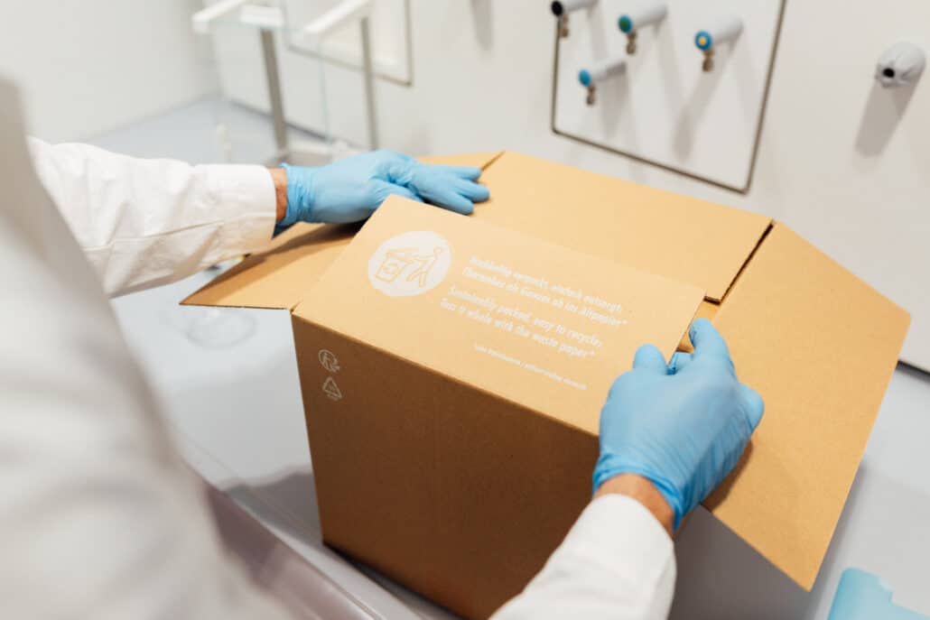 Gloved hands closing a paper-based insulated shipping carton