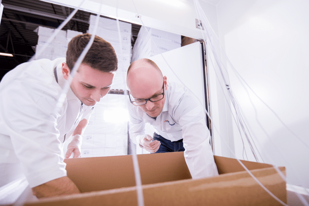 Two technicians arranging temperature sensor leads in an insulated shipper