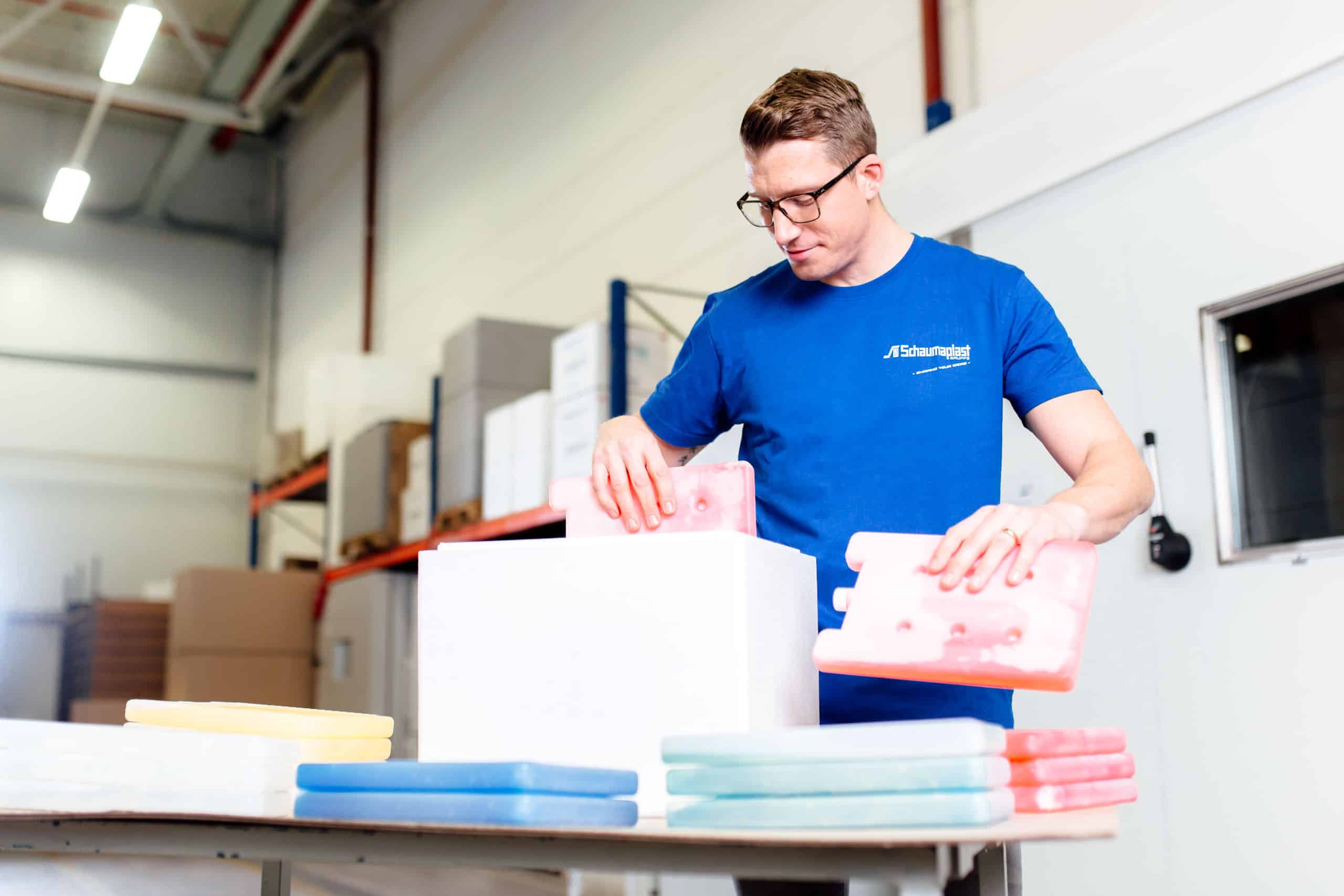 Employee placing coolant packs into an insulated shipper at a packing station