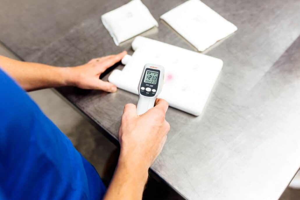 Infrared thermometer aimed at the surface of a white coolant pack